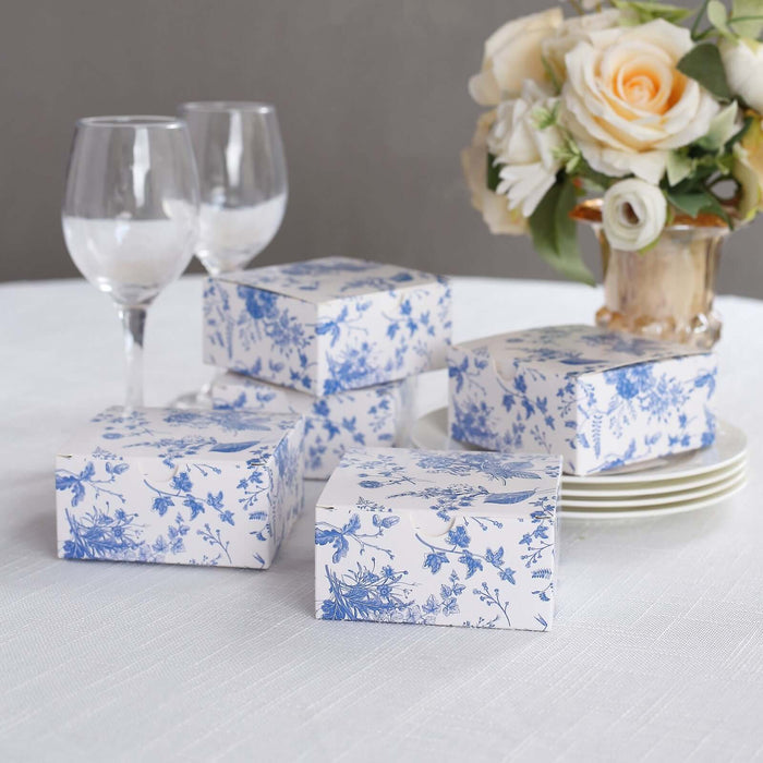 Elegant blue floral gift boxes on a table setting with roses and glassware.