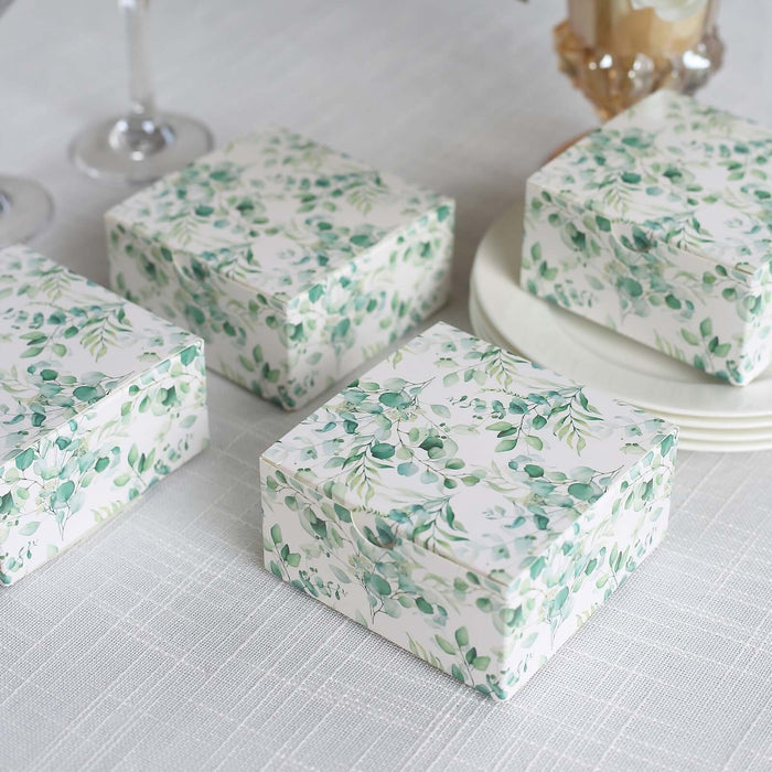 Decorative gift boxes with green foliage design on a light background.