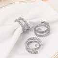 Silver glitter napkin rings on a white table setting.