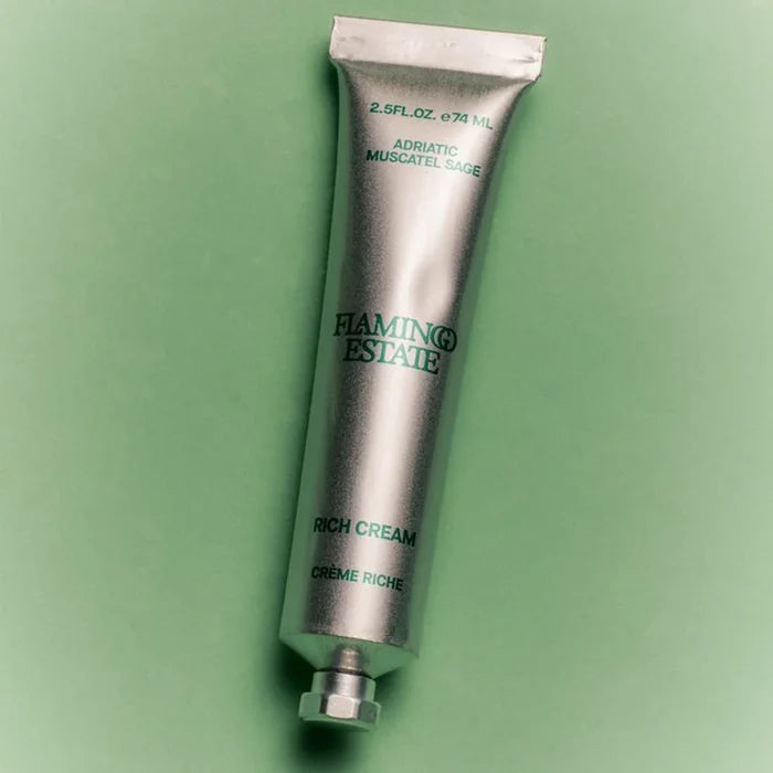 Silver tube of Flamingo Estate Rich Cream on a green background