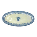 An oval ceramic serving platter with a blue and white glaze, featuring a central floral motif and a patterned border.