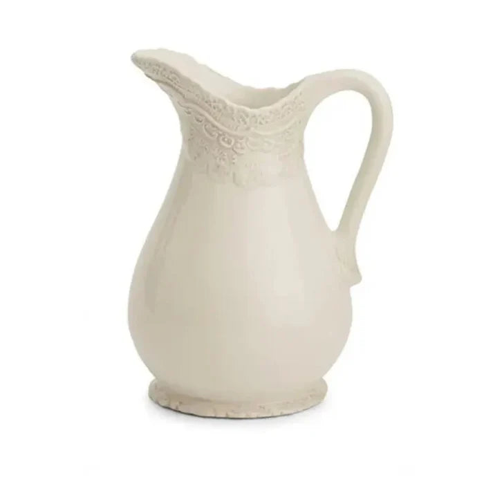 White ceramic pitcher with lacy designs sculpted around the top