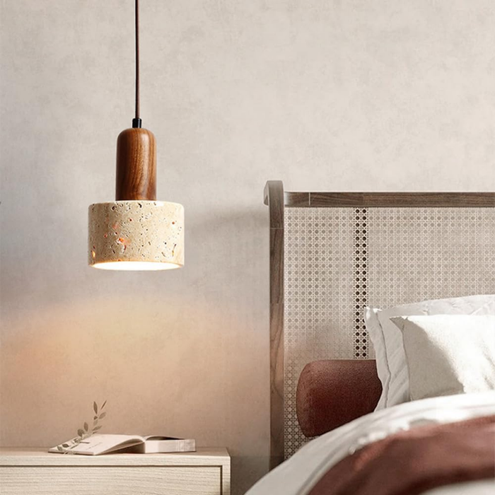 Aurelia Travertine Cylinder Pendant Light hanging above a bedside table near abstract wall art
