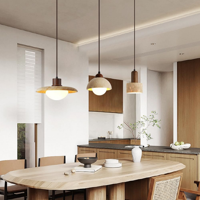 Three Aurelia Travertine Pendant Light designs hanging above a kitchen island dining table