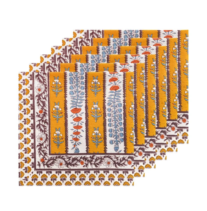 Six  napkins with a block print pattern, fanned out to show the stack. The napkins feature a mustard yellow center with blue and orange floral motifs, bordered by brown and white patterns.