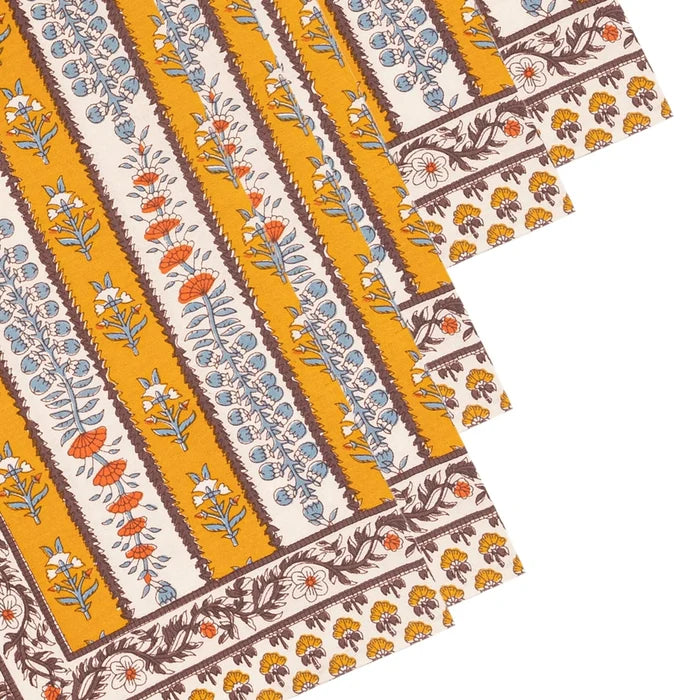 A close-up of patterned napkins arranged diagonally. The design features vertical stripes with botanical motifs in mustard yellow, cream, brown, light blue, and orange.