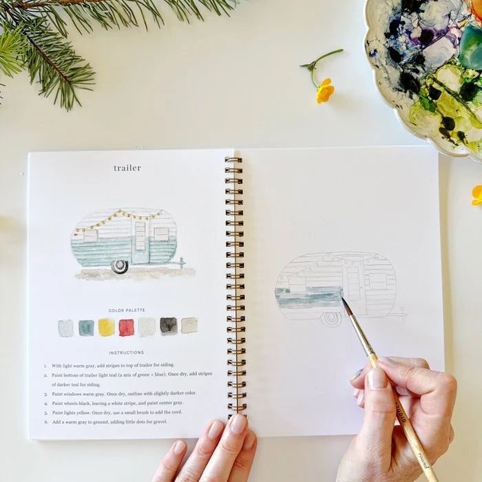 Open book with illustrations and color swatches, with a hand holding a paintbrush
