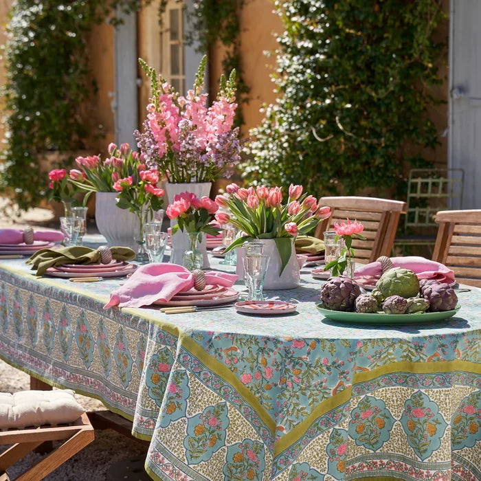 Outdoor table setting with floral arrangements and blue and green and pink floral tablecloth