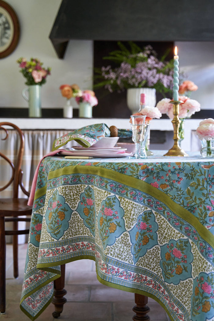 Decorative table setting with a blue floral tablecloth in a home setting.