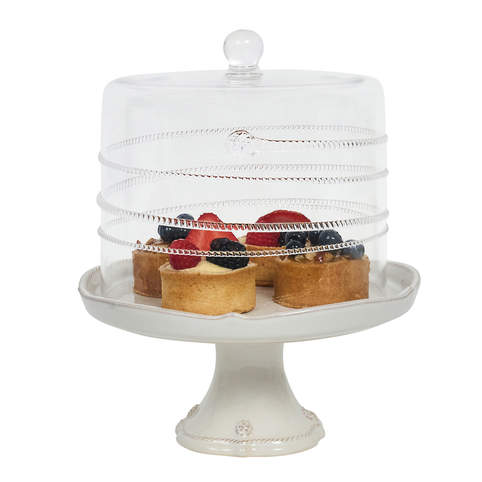 White cake stand with a glass cover displaying small pastries on a white background