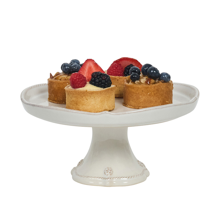 Small fruit tarts on a decorative white cake stand with a white background