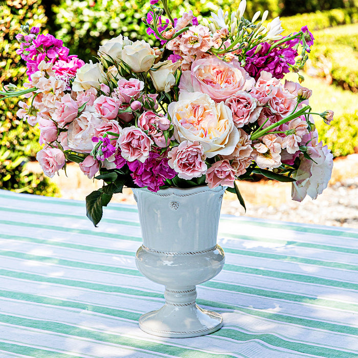 Bouquet of pink and white flowers in a decorative vase on a striped tablecloth.