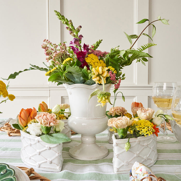 Decorative table setting with floral arrangements and a white vase.