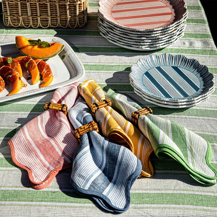 Colorful striped plates and napkins on a table with a green and white striped tablecloth.