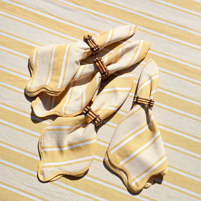 Yellow and white striped napkins with bamboo napkin rings on a yellow and white striped tablecloth