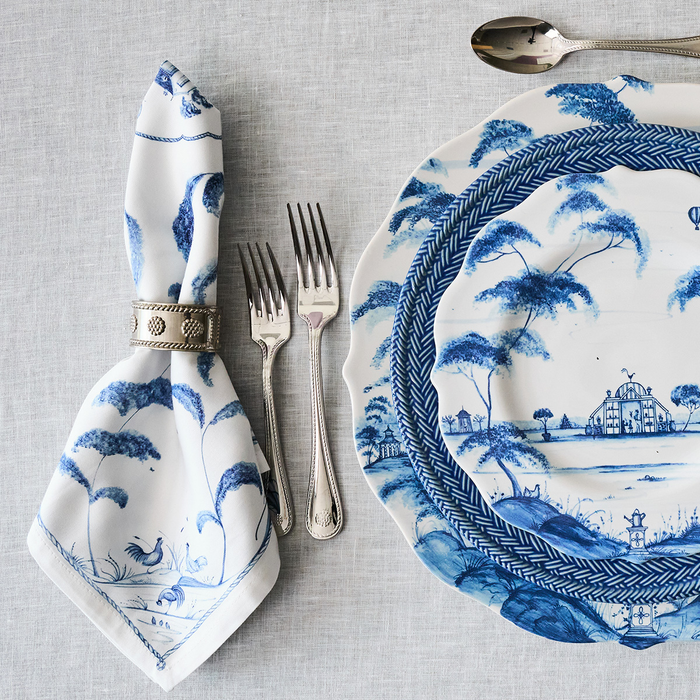 Blue and white patterned plate with napkin and cutlery on a gray tablecloth