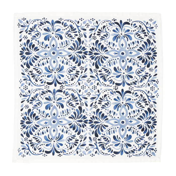 A square white fabric napkin  featuring a classic blue and navy floral damask pattern