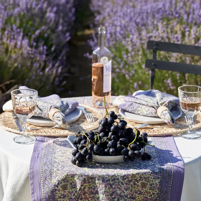 Table setting with grapes, wine glasses, and a bottle of wine in a lavender field.