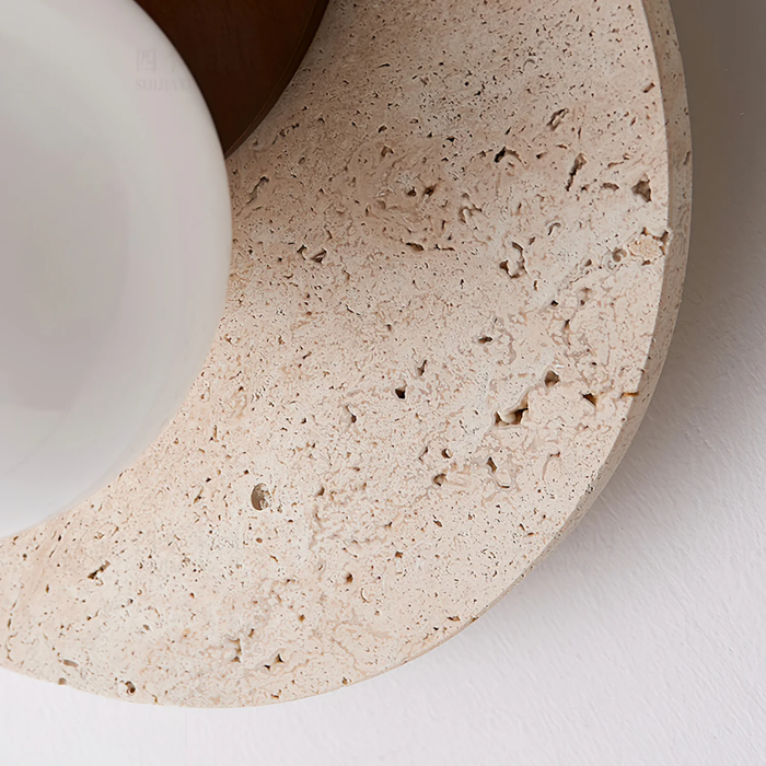 Close-up texture detail of the travertine stone disc and frosted glass globe on Lunara Wall Light