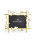 A gold-colored metal picture frame with a butterfly motif and white enamel accents, designed to hold a 5x7 photo.