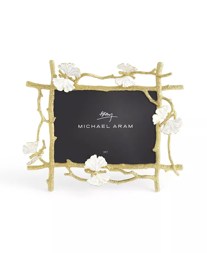 A gold-colored metal picture frame with a butterfly motif and white enamel accents, designed to hold a 5x7 photo.