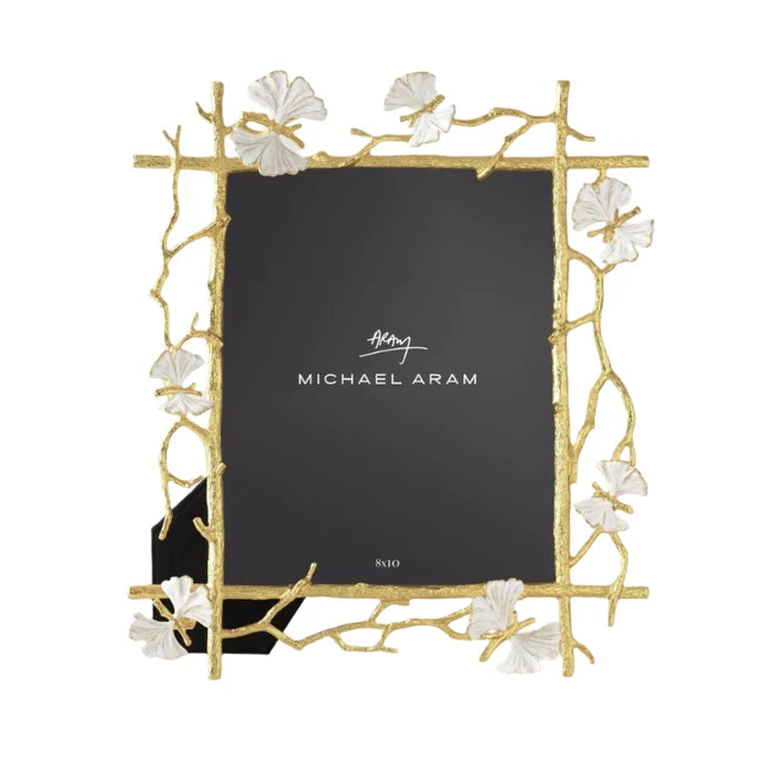 A gold-colored metal picture frame with a butterfly and ginkgo leaf design, featuring white enamel accents, from the Michael Aram brand.