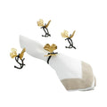 A set of four brass and gold ginkgo napkin rings and a white and beige napkin