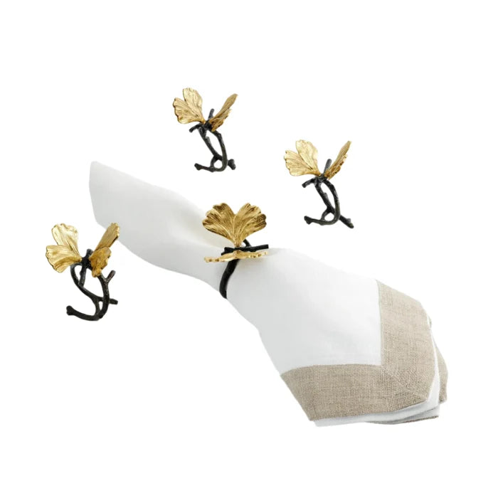 A set of four brass and gold ginkgo napkin rings and a white and beige napkin