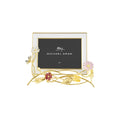 A gold-colored metal photo frame with a floral design, featuring pink and white flowers on the sides, holding a black background with the text 'Michael Aram' and '4x6'.