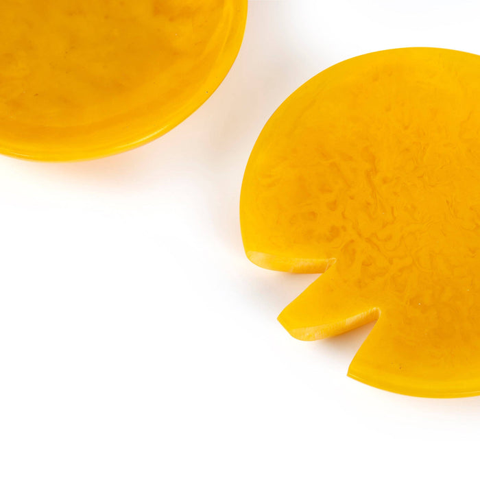 Two translucent yellow wax melts or solid shampoo bars with a textured surface, photographed on a clean white background.