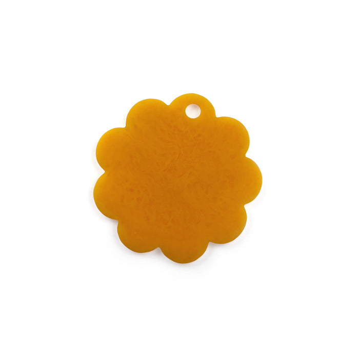 A single scalloped flower-shaped tag or charm in a translucent amber-orange color, featuring a small hanging hole at the top, shown on a plain white background.