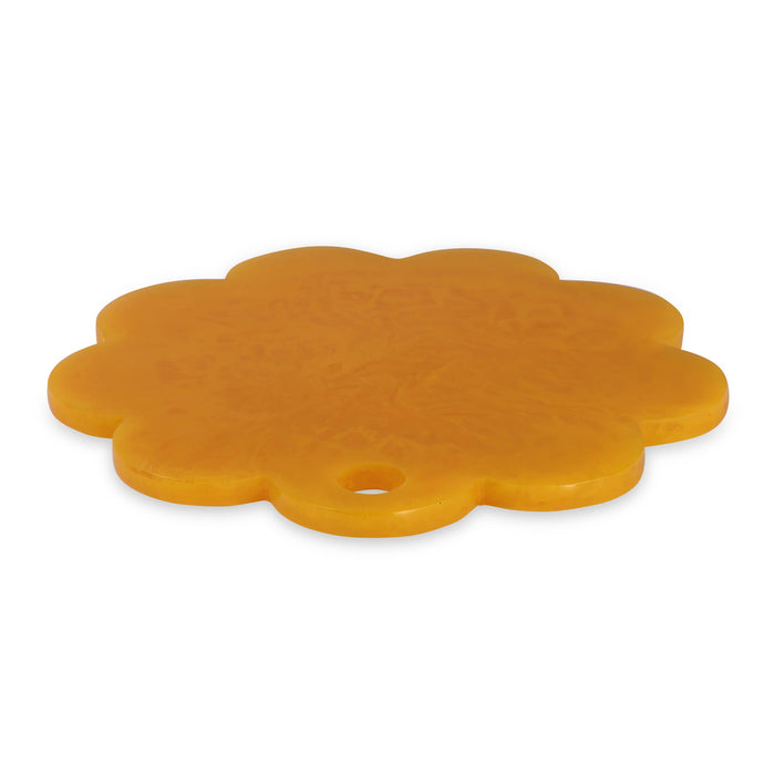 A flower-shaped orange plastic trivet or coaster with a small hole in one of its petals, shown on a plain white background.