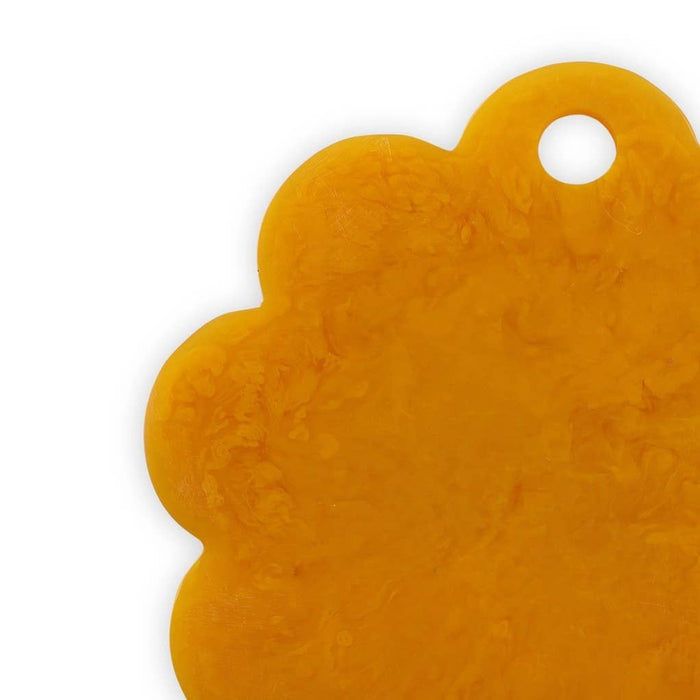 A close-up of a scalloped, cloud-shaped amber yellow tag or keychain with a hole in the top right, shown on a plain white background.