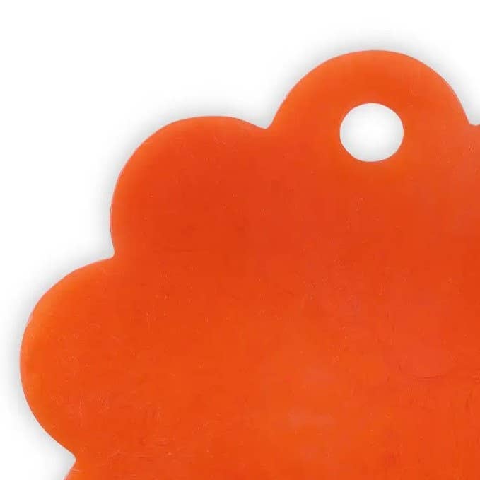 A close-up of a bright orange, scalloped-edged tag or label with a circular hole near the top right, set against a plain white background.