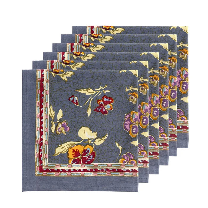A set of six square napkins with a gray-blue background and a colorful floral pattern, arranged in a cascading stack