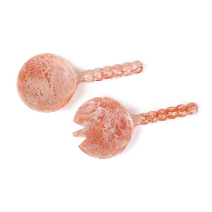 Two peach-colored stone carving utensils, one with a circular spoon-like end and one with a circular fork-like end, both featuring twisted handles, displayed on a clean white background.