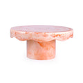 A round pedestal side table made of pink and white marbled stone, featuring a scalloped edge on the tabletop and a cylindrical base, shown on a plain white background.
