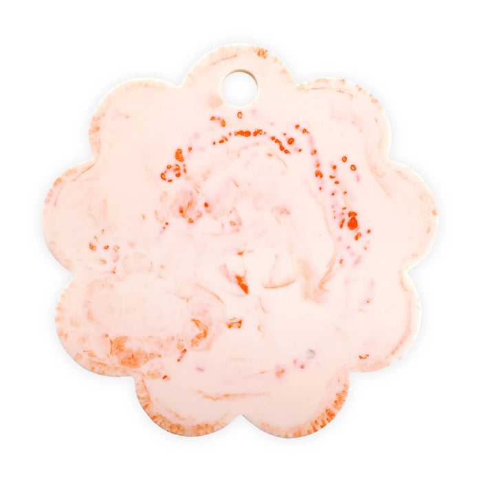 A scalloped flower-shaped tag or charm with a small hanging hole, featuring a light pink and white marbled pattern with scattered orange speckles, shown on a plain white background.