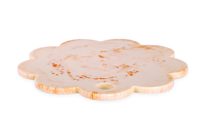 A scalloped-edge stone serving board or tray made of cream-colored stone with orange-brown marbling and a small circular hole near one end, shown on a plain white background.