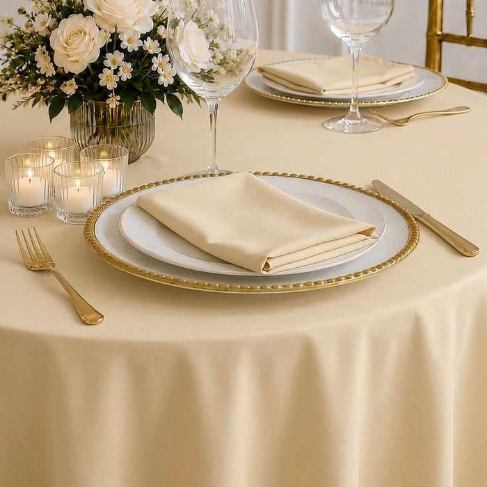 Beige round tablecloth on elegantly set dining table.