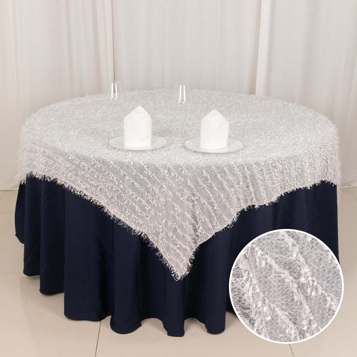 Round white tablecloth with textured fringe, styled on a navy table.