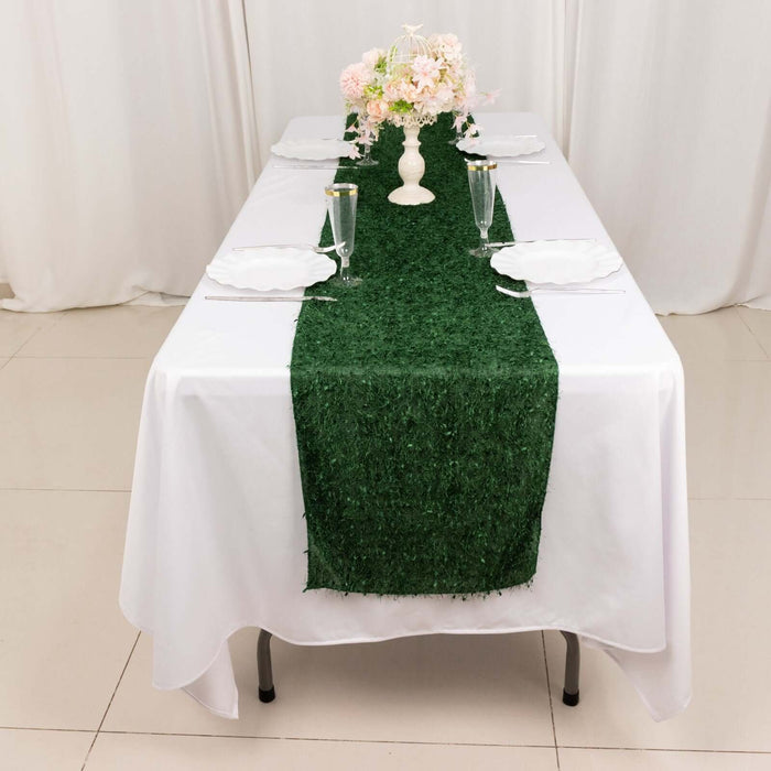Green grass table runner on a set dining table with floral centerpiece.