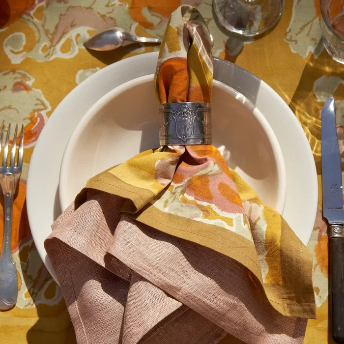 Decorative fall table setting with leaf patterned napkins and a colorful tablecloth.