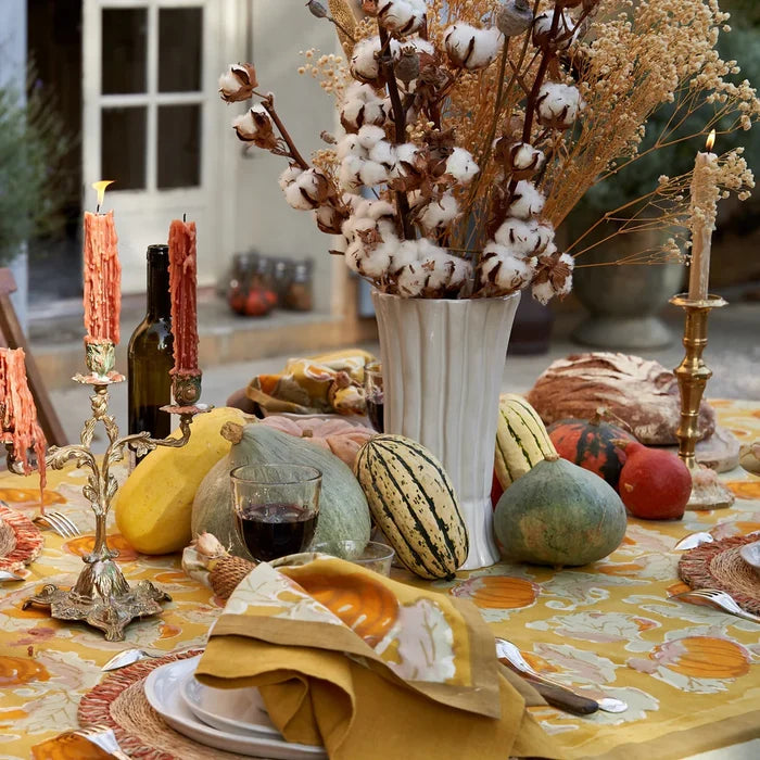Decorative table setting with pumpkins, candles, and a cotton arrangement.