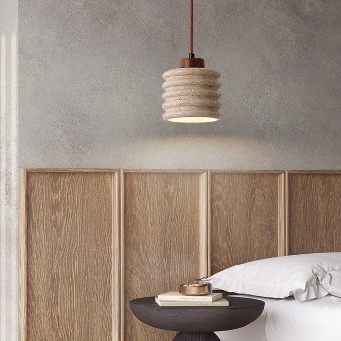 Ribelle Travertine Pendant Light - lifestyle above a bedside table with wood-panel headboard