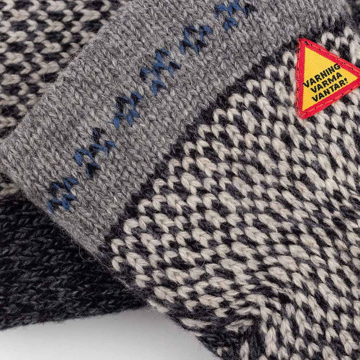 Close-up of a knitted fabric with a pattern and a warning label on a white background