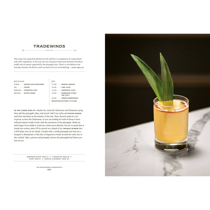 Cocktail in a glass with a green garnish on a marble surface, next to a recipe for  cocktail called Tradewinds