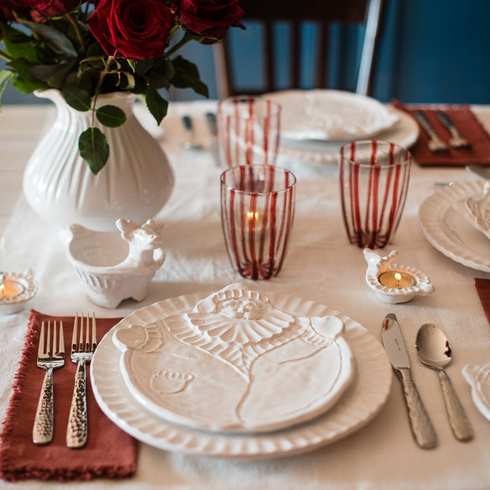 Elegant table setting with red roses, candles, and decorative santa plate