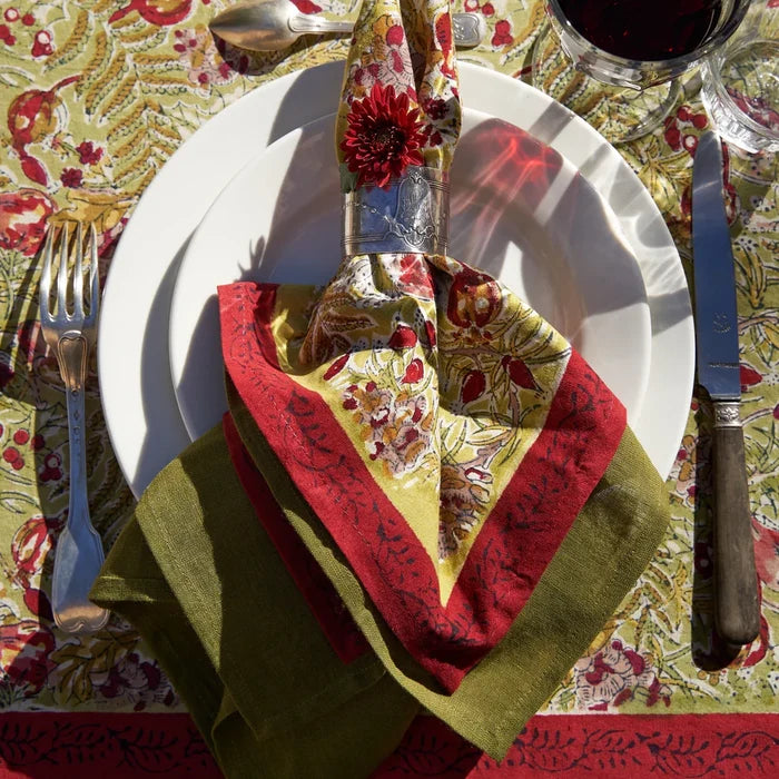 Decorative table setting with red and green napkins and a patterned tablecloth.