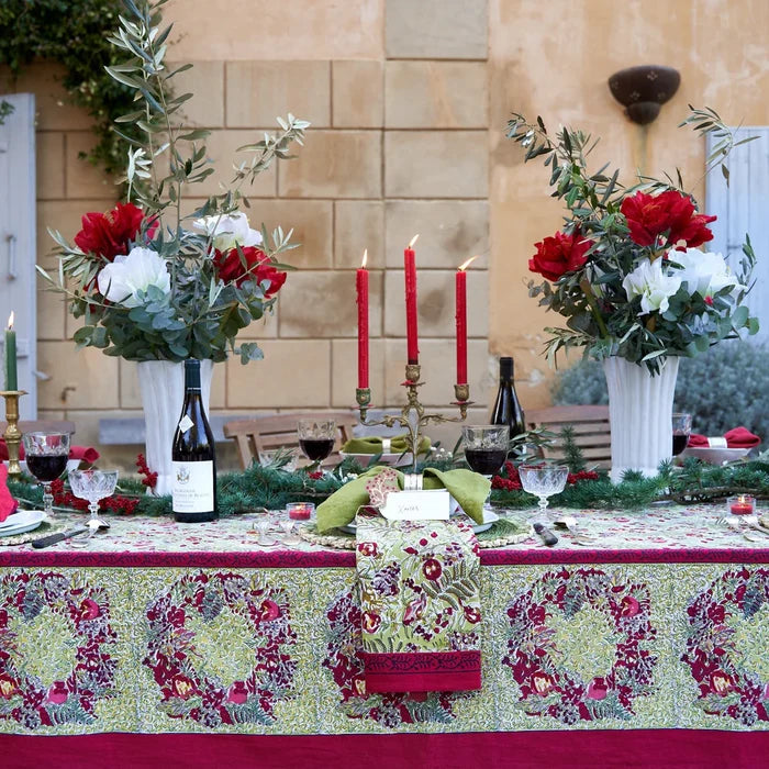 Decorated table with holiday floral centerpieces, candles, and wine glasses outdoors.